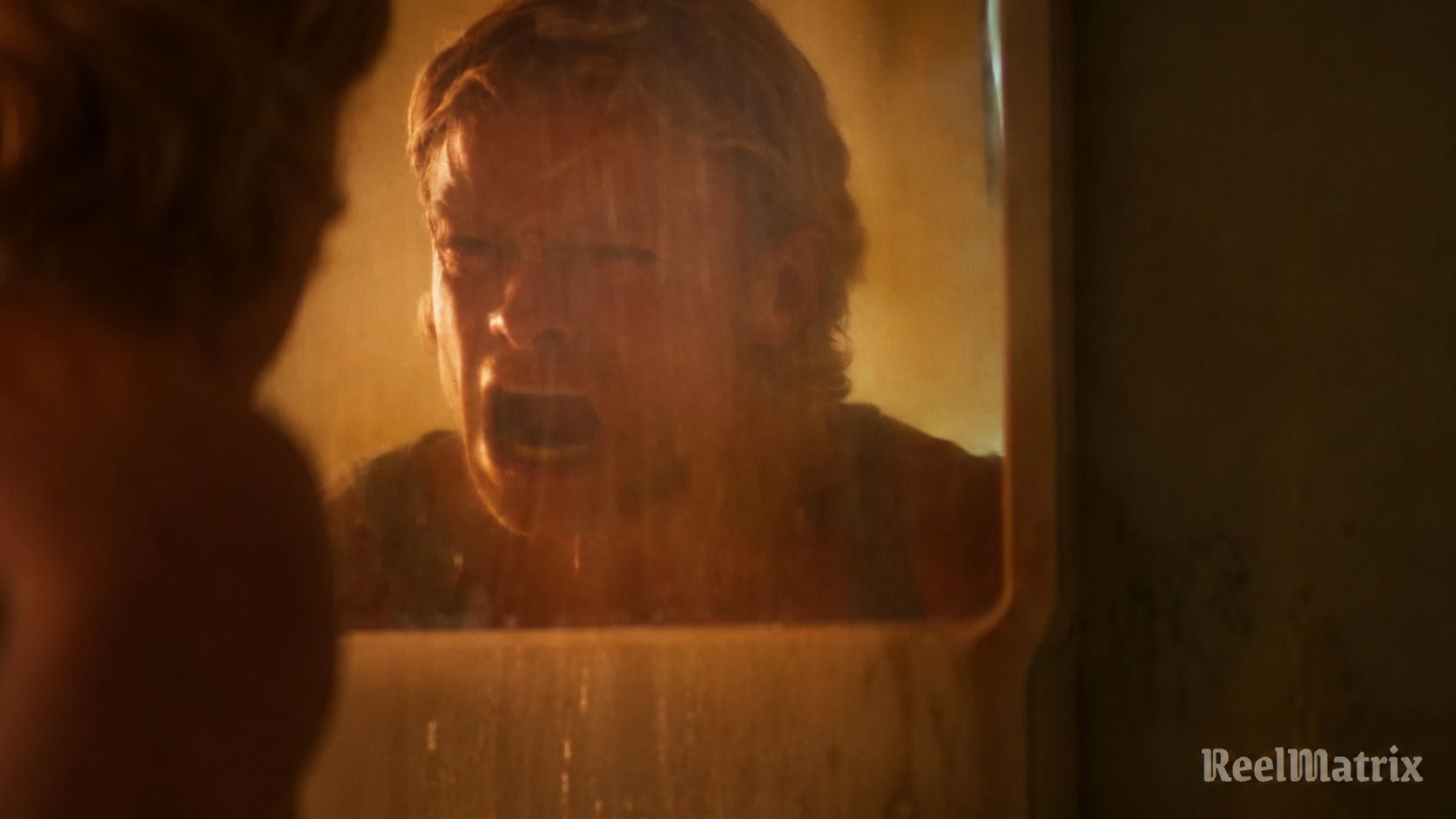 Matt Hagen screams at his reflection in an amber-lit mirror, with the ReelMatrix logo at bottom right.